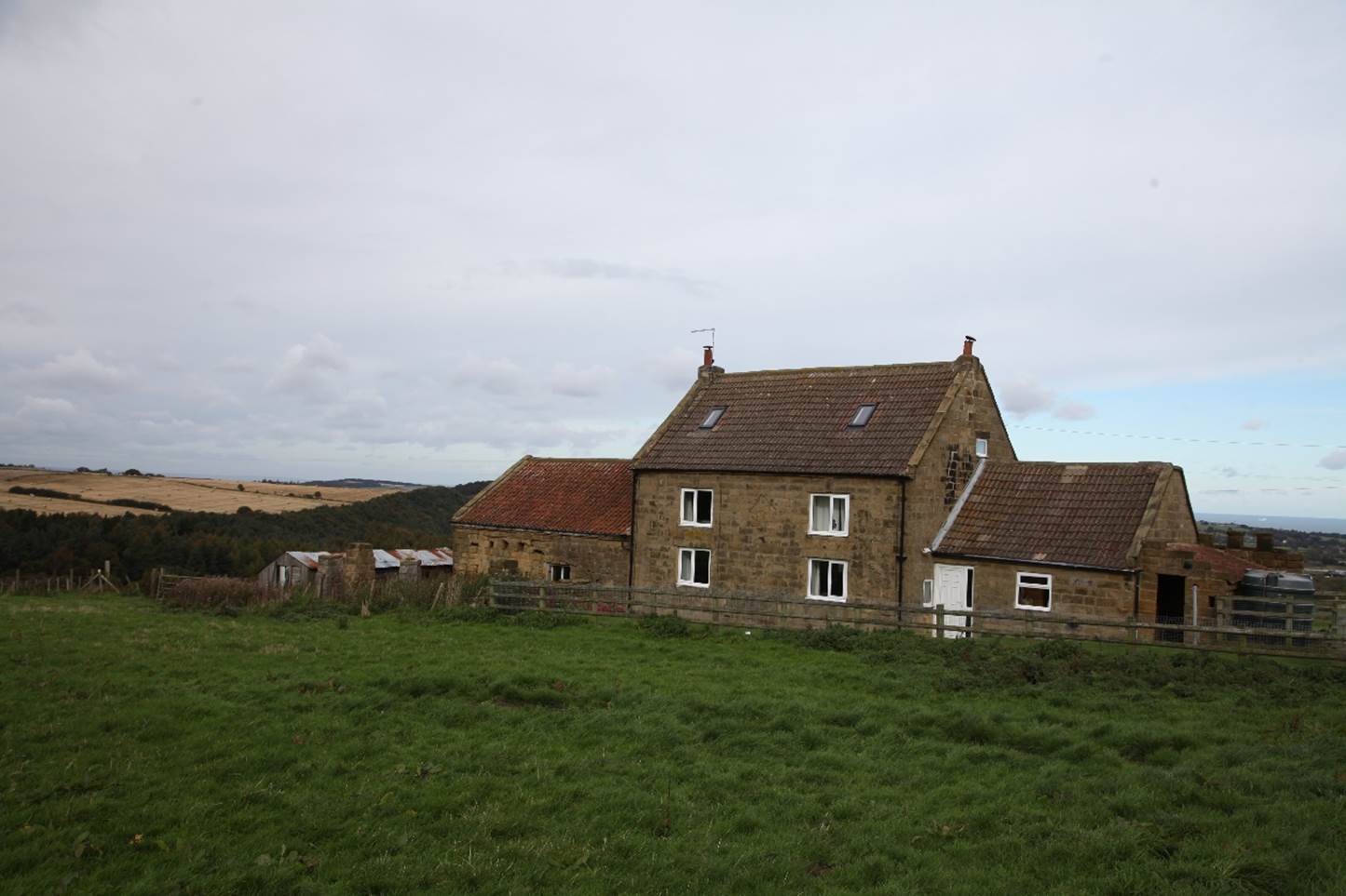 A stone house with a grassy field
Description automatically generated
